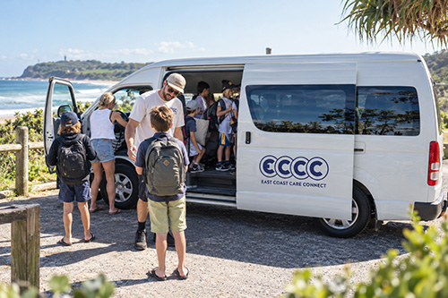 East Coast Care Connect transport vehicle with participants and support workers in a coastal setting.